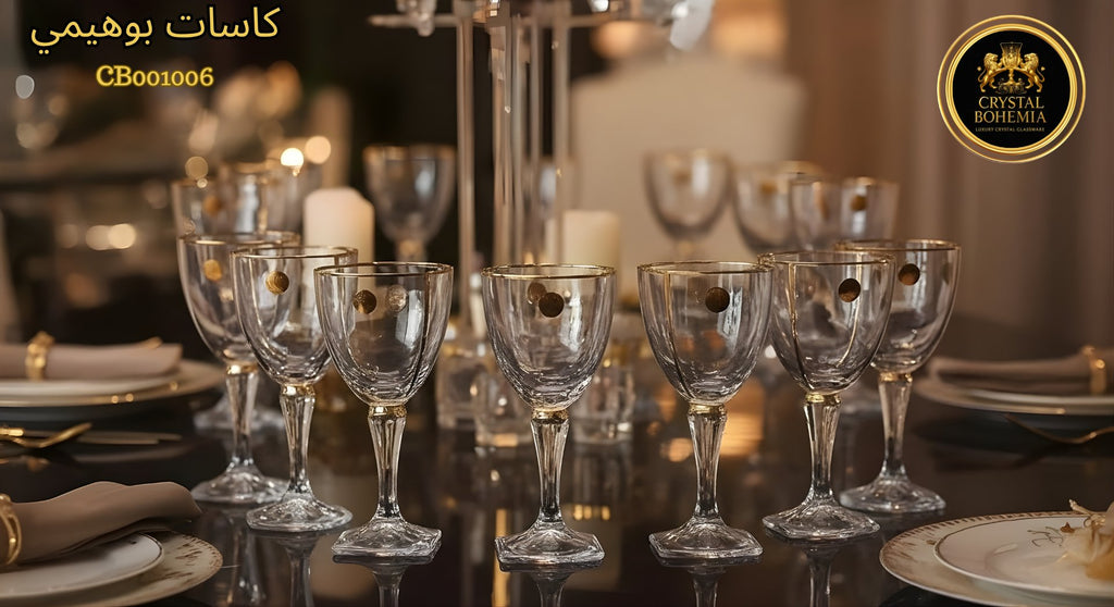 Set of crystal wine glasses on a dining table with candles and plates in the background.